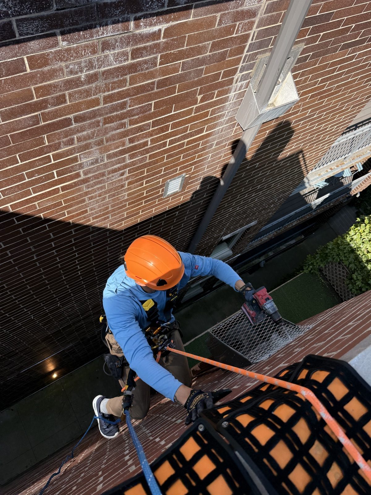 Technician rappelling down a four-story brick facade in Old Town, Chicago