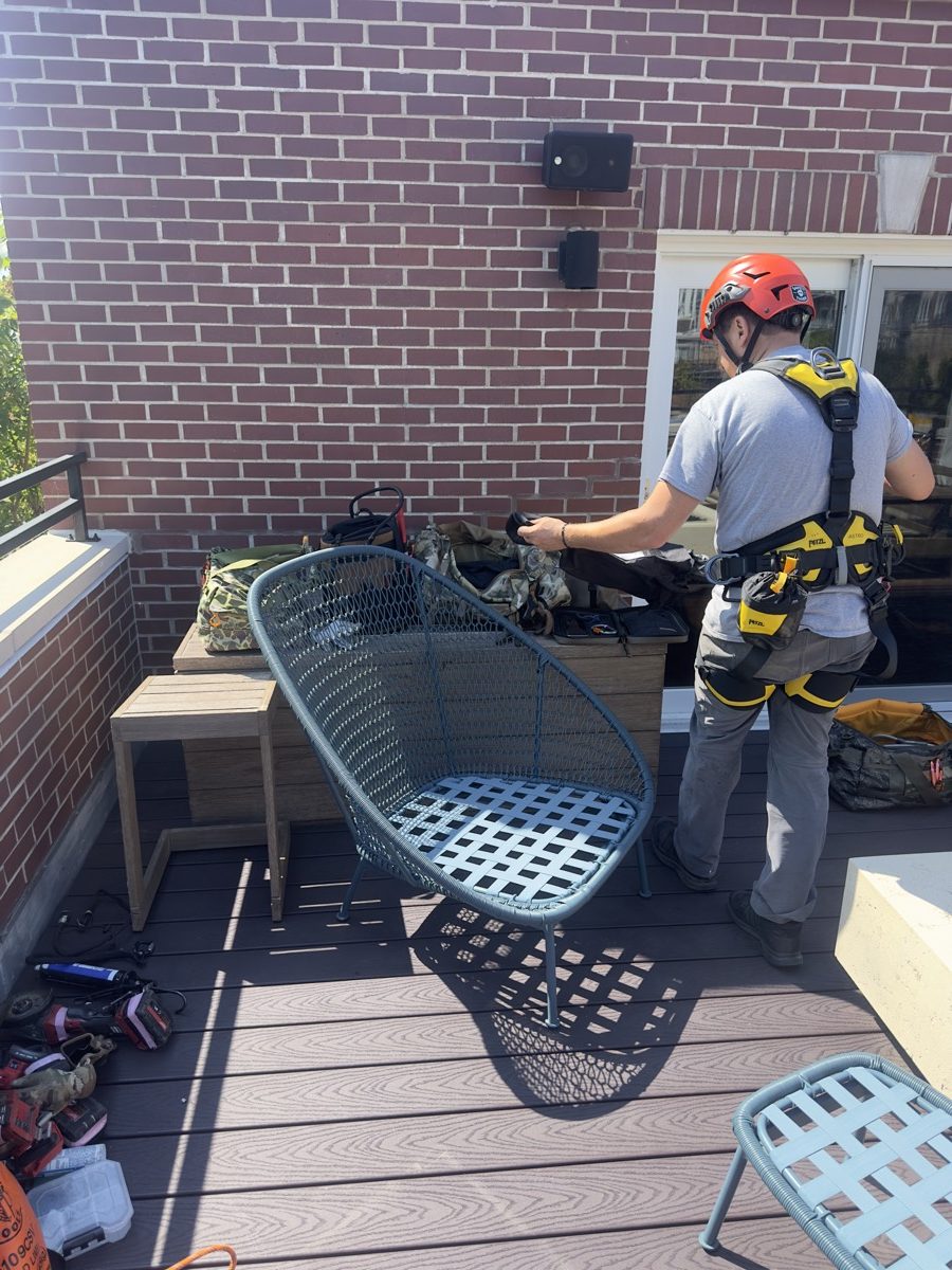 Rope access technician checking harness and gear on a fourth-floor roof deck in Old Town, Chicago